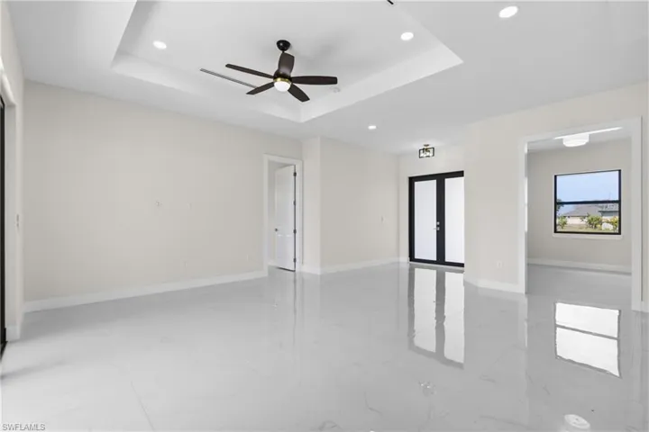 Spare room featuring recessed lighting, french doors, ceiling fan, light marble finish flooring, and a tray ceiling
