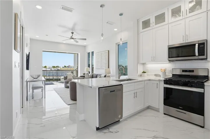 Kitchen with appliances with stainless steel finishes, light marble finish floors, tasteful backsplash, white cabinets, and pendant lighting - Virtually Edited Image