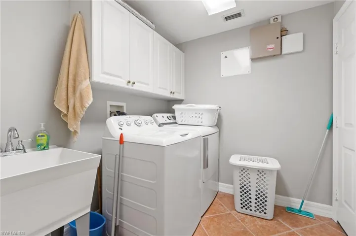 Spacious Laundry Room with many cabinets, great lighting and large wash sink. Door to garage is on the right.