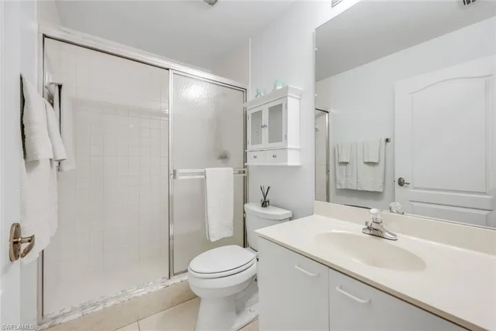 Full bath with a shower stall, vanity, and light tile patterned flooring