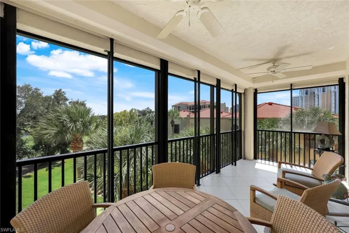 Sunroom / solarium featuring ceiling fan, a balcony, tile patterned flooring, expansive windows, and a textured ceiling