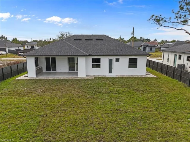Rear view of house with a patio, stucco siding, roof with shingles, a fenced backyard, and a residential view