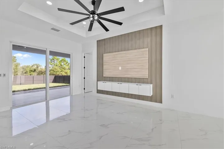 Spare room with light marble finish floors, an accent wall, recessed lighting, ceiling fan, and a tray ceiling