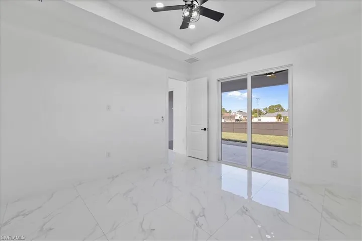 Empty room featuring ceiling fan and a raised ceiling