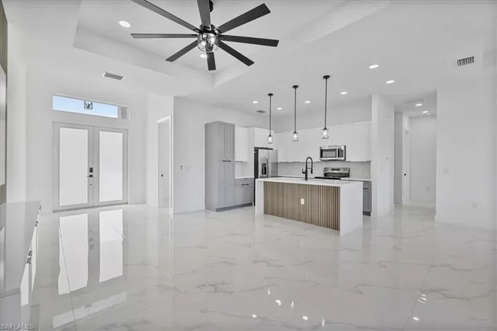Kitchen with open floor plan, hanging light fixtures, a center island with sink, french doors, and recessed lighting