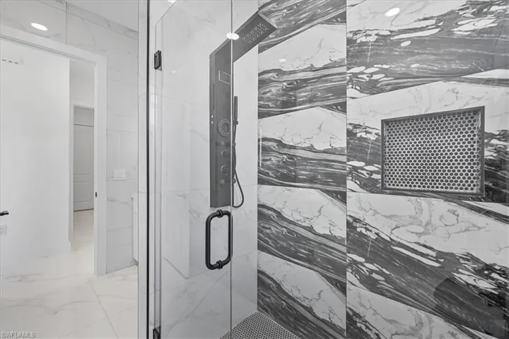 Bathroom featuring a marble finish shower and light marble finish flooring