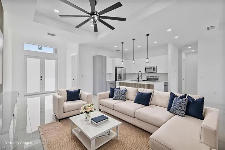 Living room featuring recessed lighting, a ceiling fan, a tray ceiling, french doors, and light tile patterned flooring