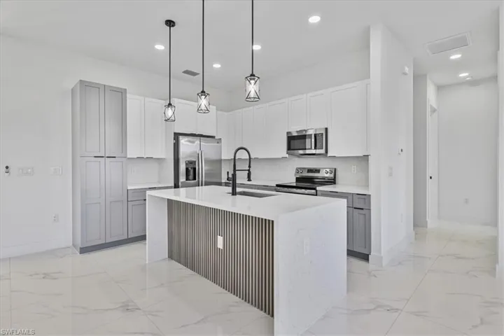 Kitchen with hanging light fixtures, stainless steel appliances, light stone counters, decorative backsplash, and recessed lighting