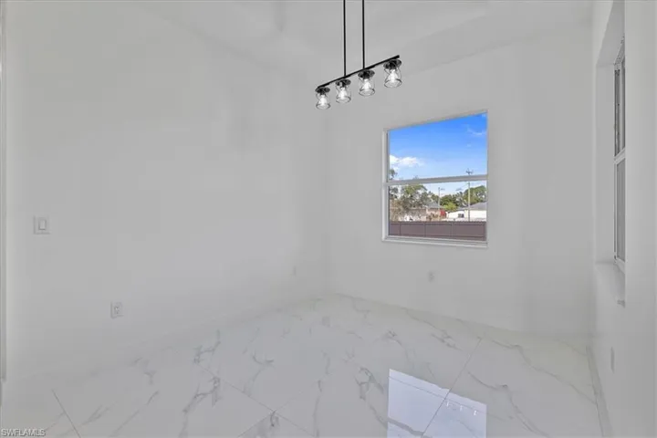 Unfurnished dining area with baseboards and marble look tiles