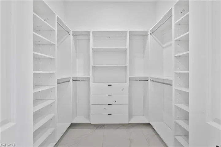 Walk in closet featuring light marble finish flooring