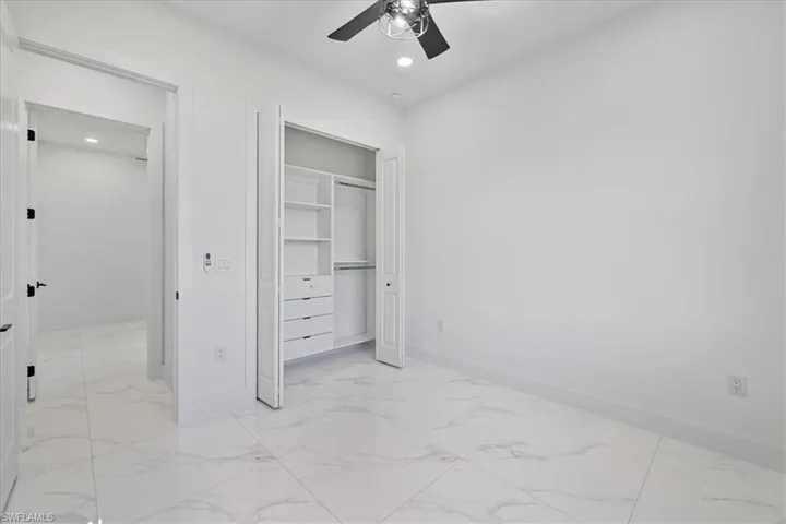 Unfurnished bedroom featuring light marble finish floors, recessed lighting, a closet, and a ceiling fan
