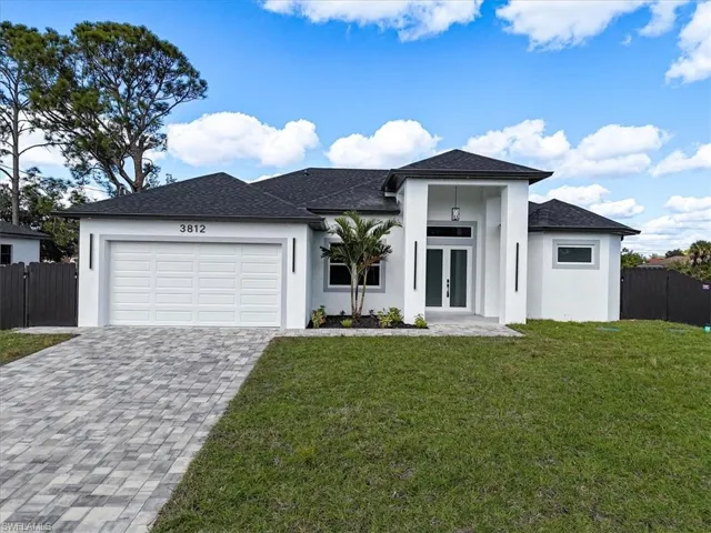 View of front of home with stucco siding, roof with shingles, french doors, decorative driveway, and a garage