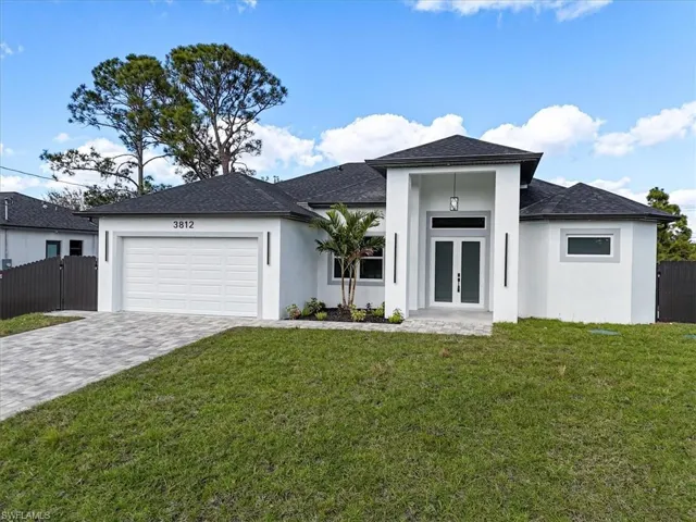 View of front of property featuring stucco siding, roof with shingles, decorative driveway, and french doors