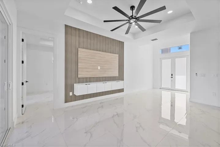 Unfurnished room featuring light marble finish floors, french doors, recessed lighting, a raised ceiling, and a ceiling fan