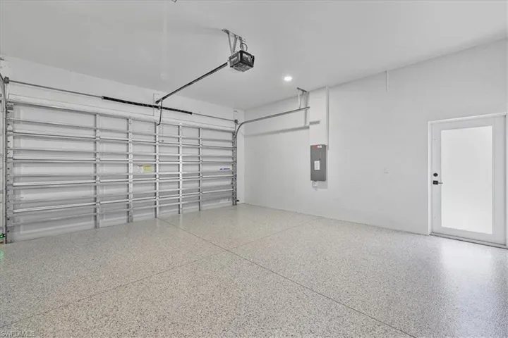 Garage featuring electric panel, a garage door opener, and recessed lighting