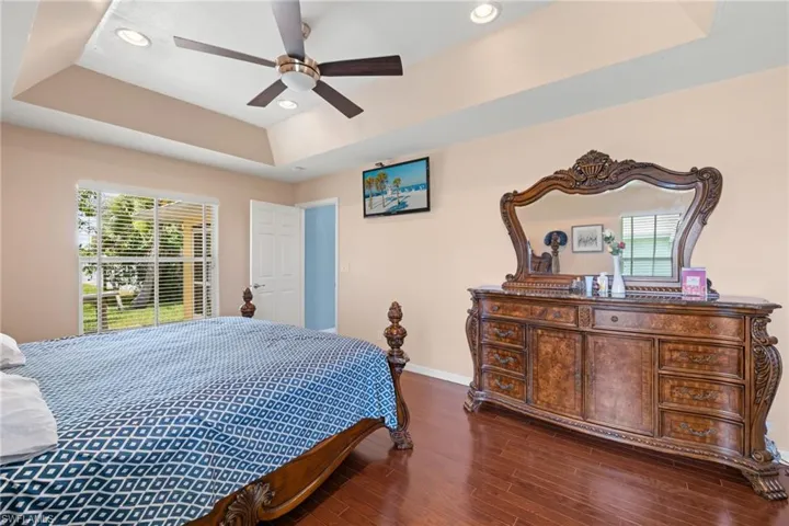 Bedroom with ceiling fan, dark hardwood / wood-style flooring, and a raised ceiling