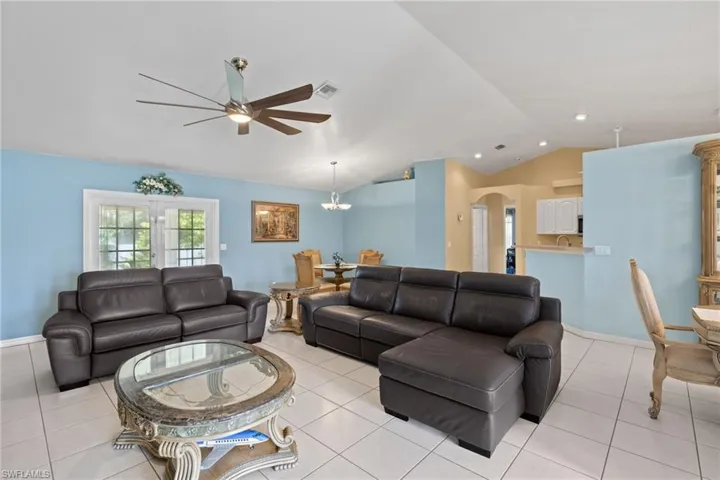Living room with light tile patterned flooring, lofted ceiling, sink, and ceiling fan