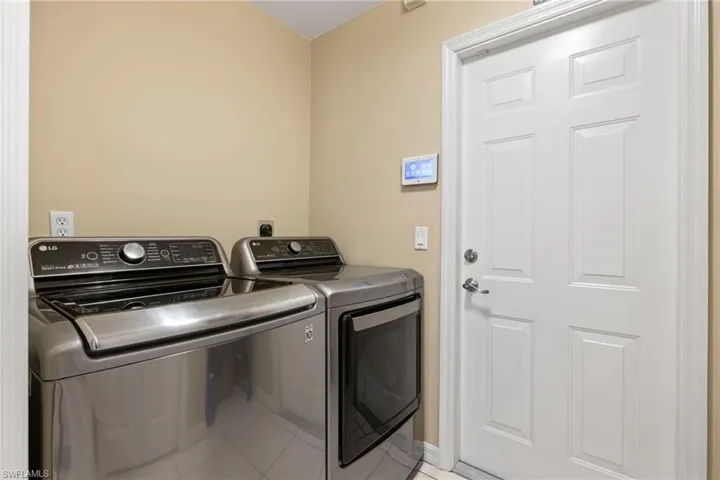 Clothes washing area with washer and dryer and light tile patterned floors