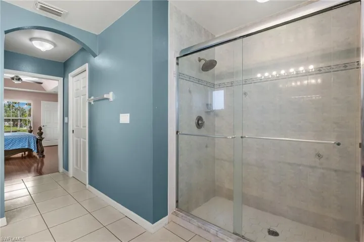 Bathroom featuring a shower with shower door, tile patterned flooring, and ceiling fan