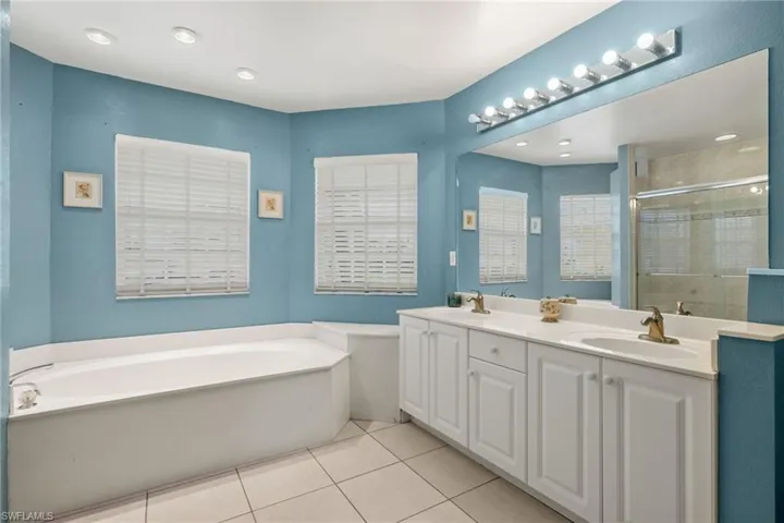 Bathroom featuring tile patterned flooring, dual bowl vanity, and a bathtub