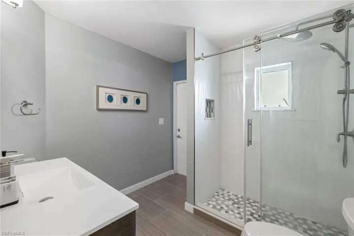 Bathroom featuring vanity, toilet, and an enclosed shower