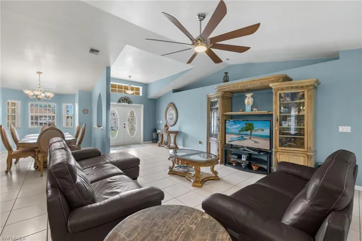 Tiled living room featuring ceiling fan with notable chandelier