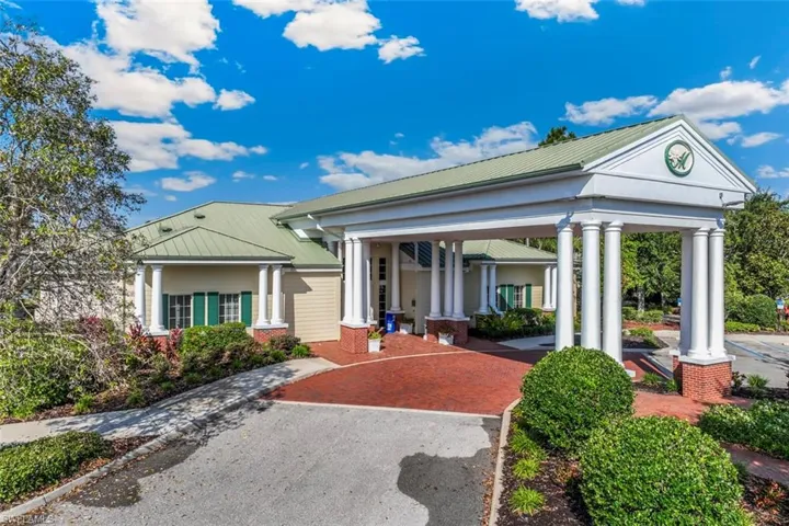The property features a distinctive entrance with a classic portico supported by columns, a green metal roof, and an inviting brick paver driveway