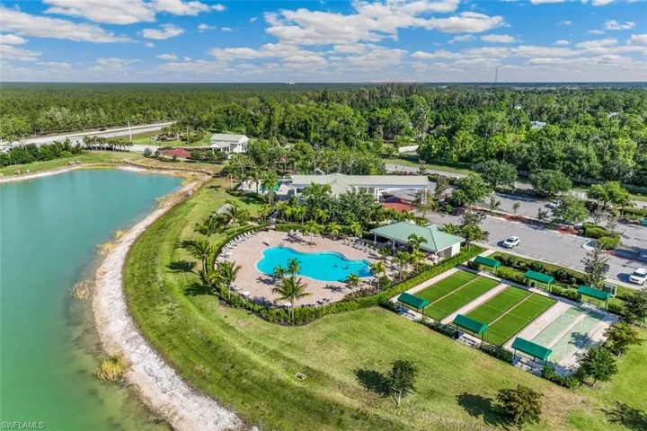 An aerial view of the property showing a large swimming pool, several bocce ball courts, and a serene lake