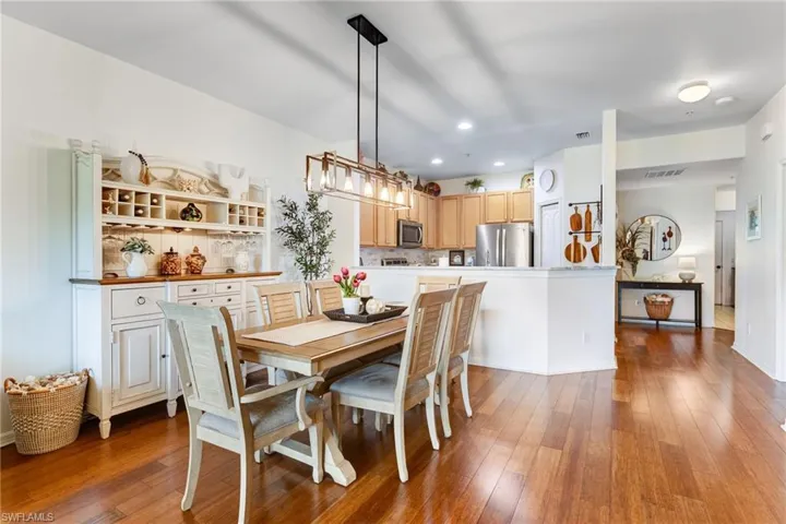 Open-concept living space featuring wood-finish flooring, recessed lighting, and a modern linear chandelier