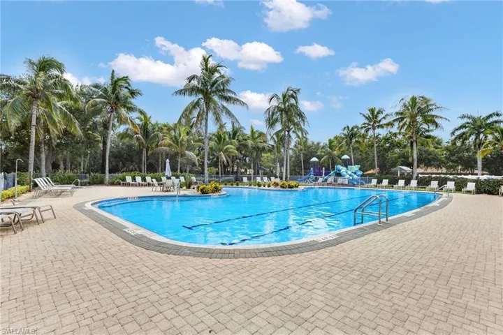 Expansive pool deck with paver surfacing, large swimming pool with lap lanes, and surrounding tropical foliage