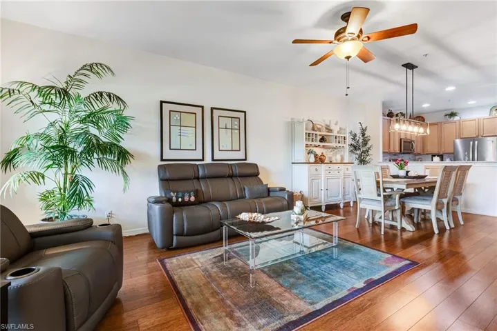 Hardwood flooring, ceiling fan, white built-in cabinetry, kitchen with wood-finish cabinetry, and stainless steel appliances
