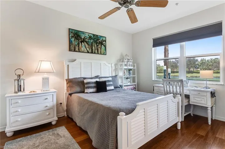 Hardwood-finish flooring, ceiling fan, and large window with roller shade