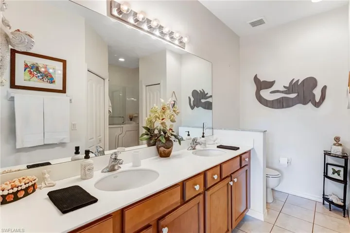 Dual vanity with undermount sinks, wood-finish cabinetry, and a large wall-mounted mirror