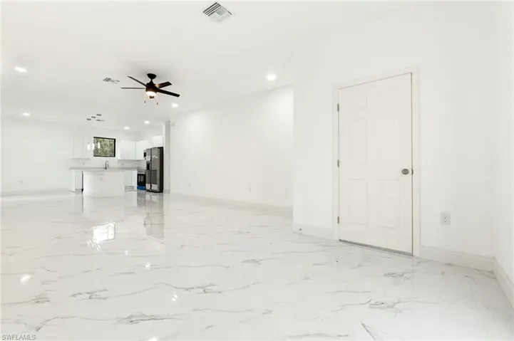 Unfurnished living room with a ceiling fan, recessed lighting, and light marble finish floors