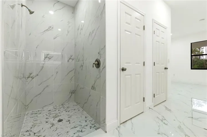 Bathroom with a marble finish shower and marble finish floors