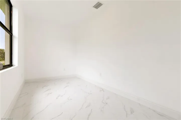 Spare room featuring marble finish floors and baseboards