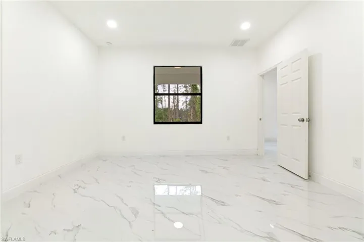 Empty room featuring light marble finish floors and recessed lighting