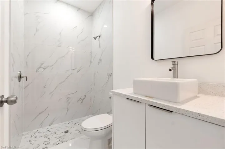 Bathroom featuring vanity and a marble finish shower