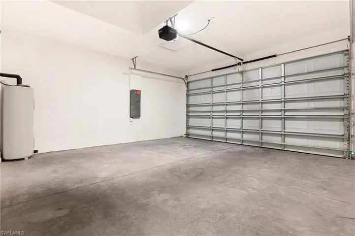 Garage with water heater, electric panel, and a garage door opener