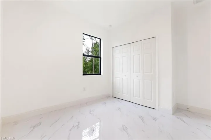 Unfurnished bedroom with light marble finish floors and a closet