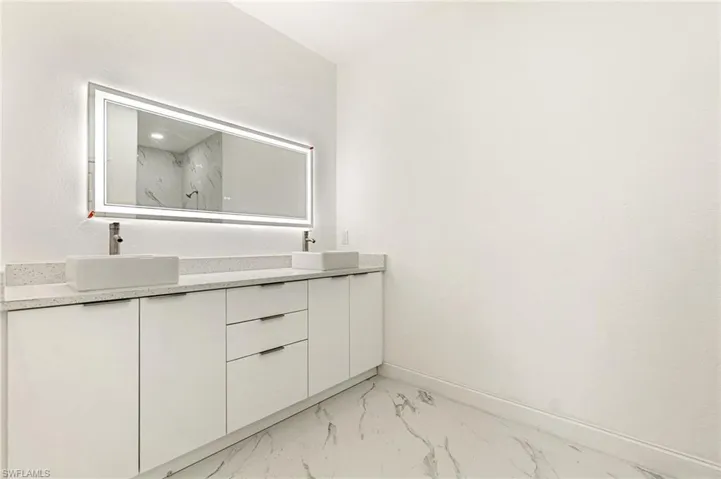 Bathroom with marble finish floors, double vanity, and a marble finish shower