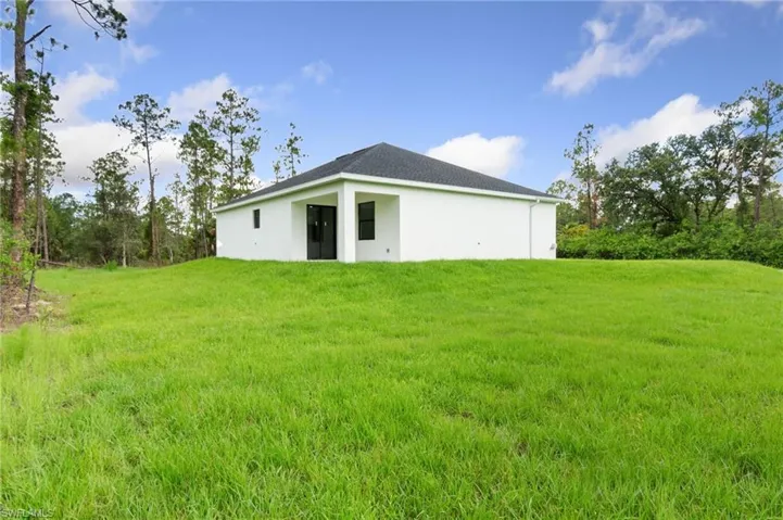 Rear view of property featuring stucco siding and a yard