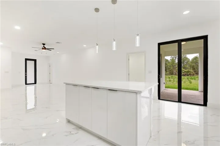 Kitchen featuring light marble finish floors, white cabinets, modern cabinets, hanging light fixtures, and recessed lighting
