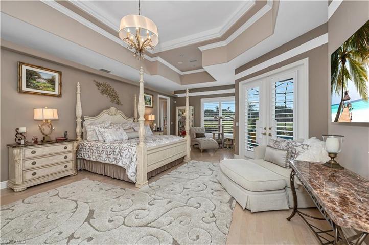 Oversized Primary Bedroom Suite with crown moulding, raised ceilings, wood floors and French doors leading to pool area. Adjacent to massive walk-in closet and pool bath