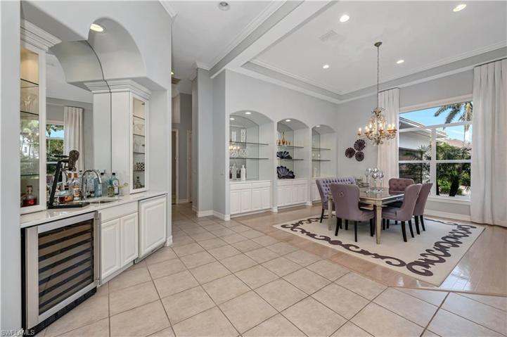 Dining room showcases a wet bar,  Uline refrigerator and wine cooler. Lighted glass enclosed cabinetry with glass shelving supplement the glass shelving and storage nooks in the dining room