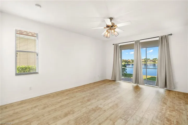 Spare room with ceiling fan, a water view, light wood-type flooring, and a smoke detector