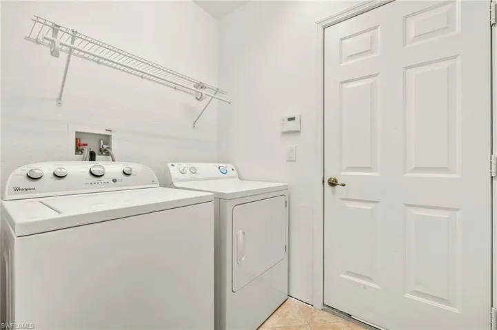 Laundry room with independent washer and dryer and light tile patterned floors