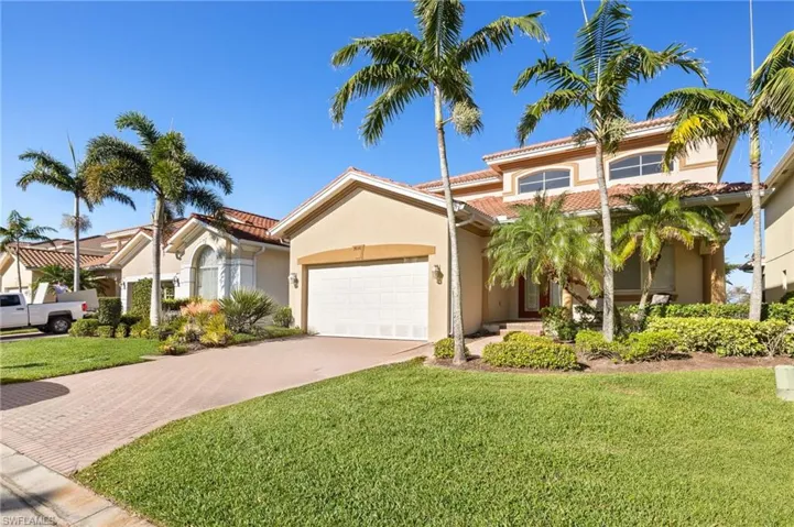 Mediterranean / spanish-style home with decorative driveway, stucco siding, a front yard, an attached garage, and a tile roof