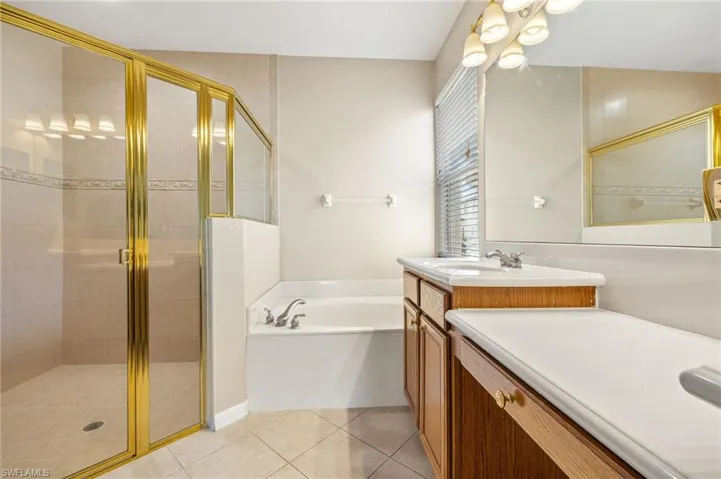 Bathroom featuring a garden tub, vanity, a shower stall, and light tile patterned floors