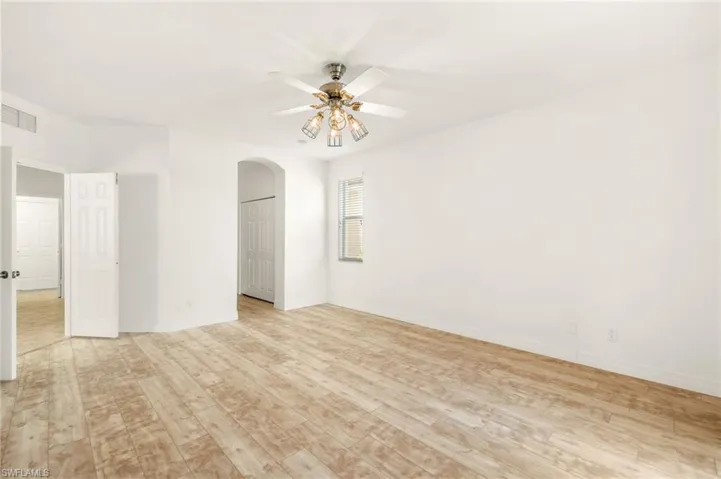 Unfurnished room featuring a ceiling fan, light wood finished floors, and arched walkways